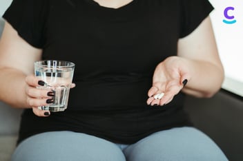 Mujer a punto de ingerir pastillas para bajar de peso