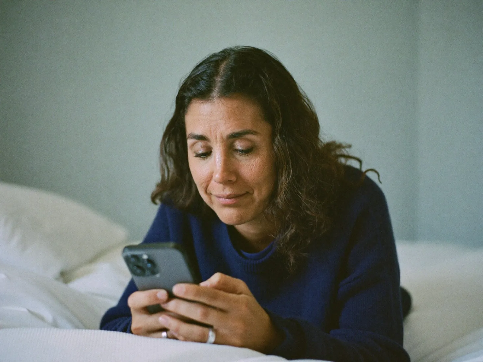 Mujer respondiendo su evaluación en el celular desde la cama