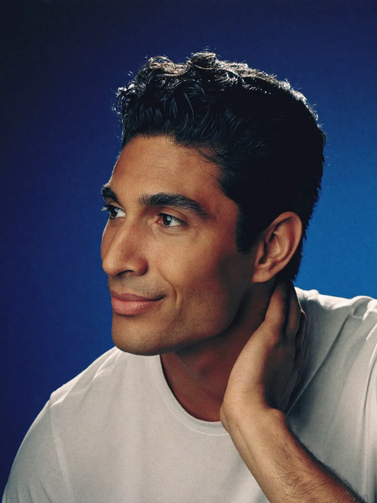 Hombre sonriendo con la mano en el cabello